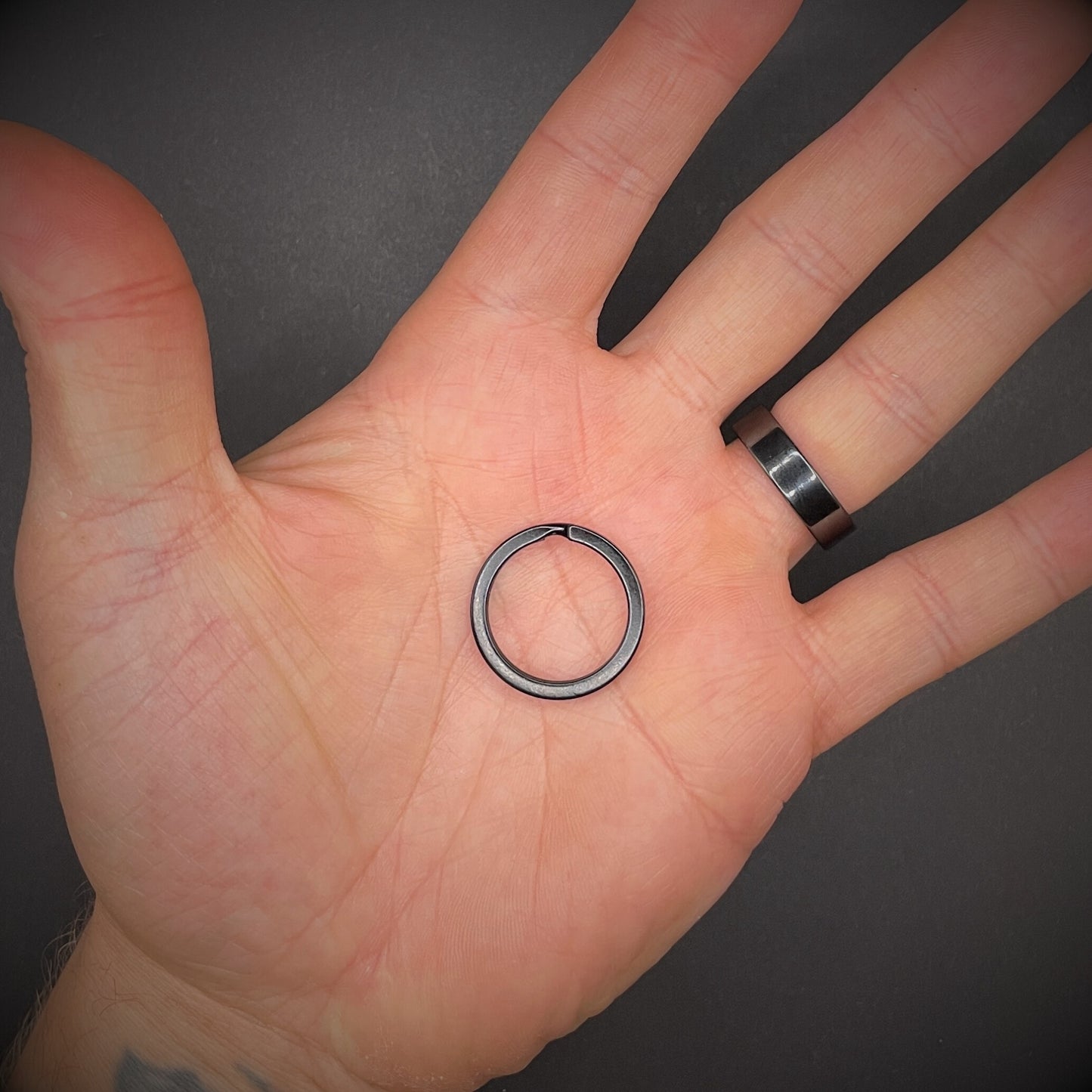 Black Split ring arranged in an open palm over a dark grey background