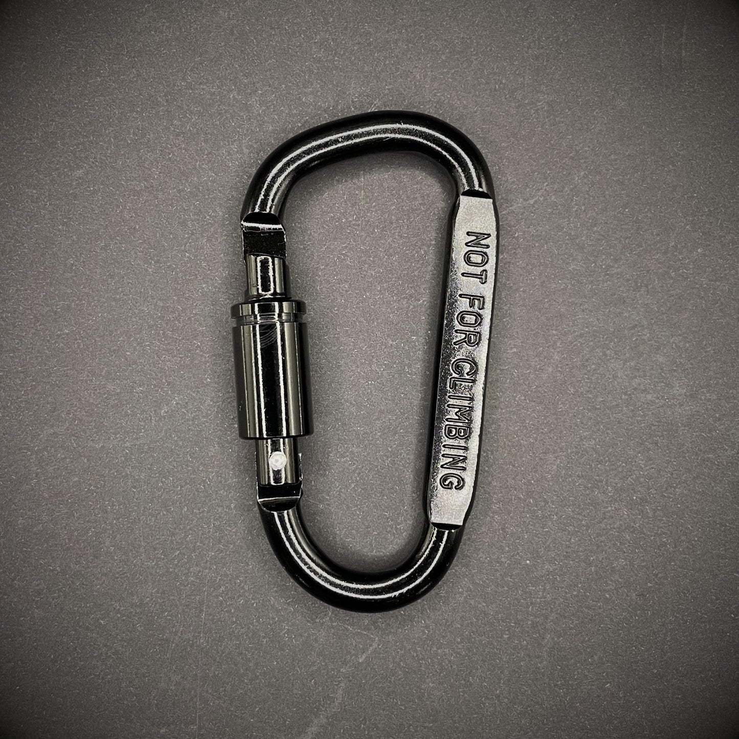Black carabiner marked 'NOT FOR CLIMBING' on a dark grey background.
