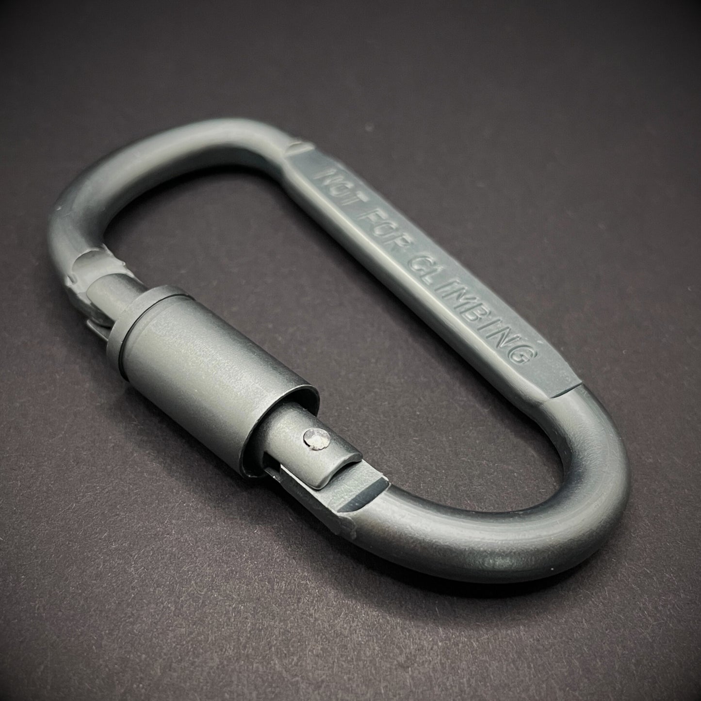 Grey carabiner marked 'NOT FOR CLIMBING' on a dark grey background.