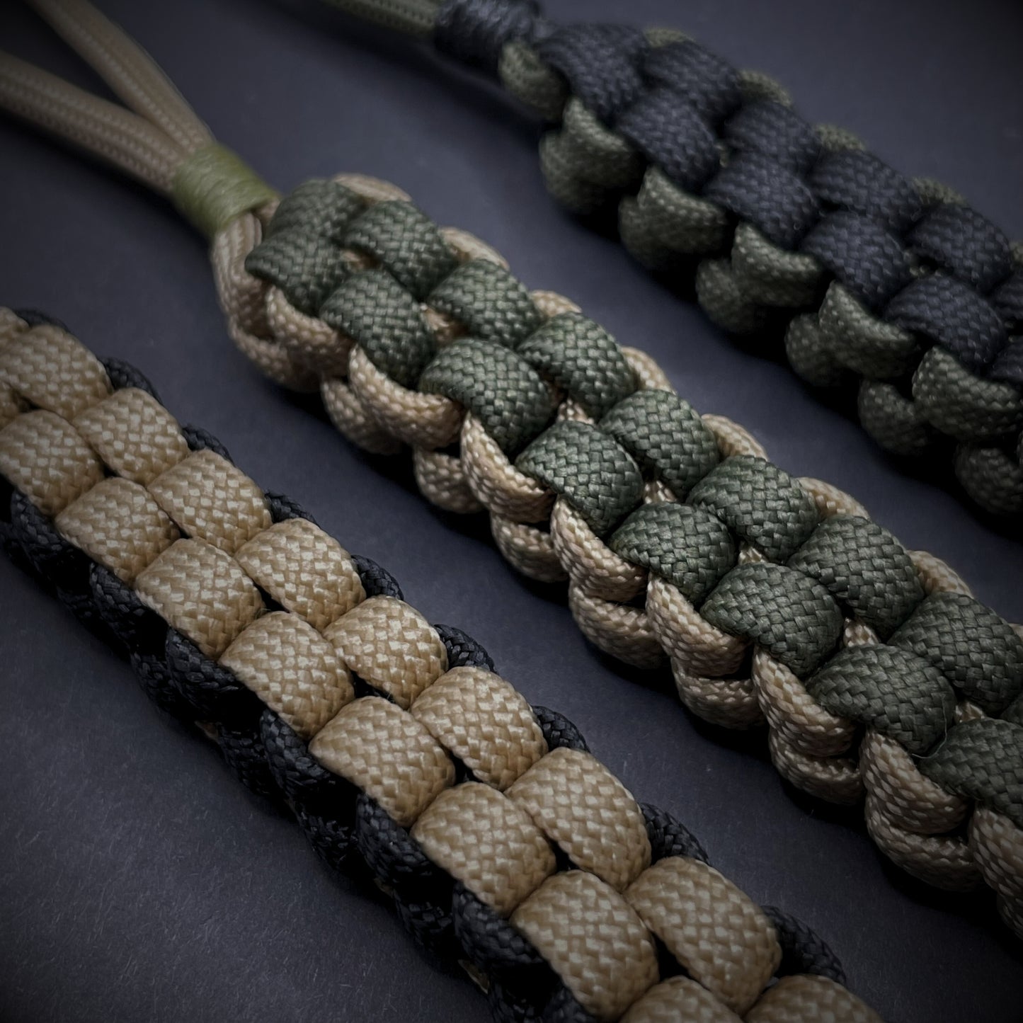 Flat lay of a 3 550 Paracord knife lanyards on a dark grey background
