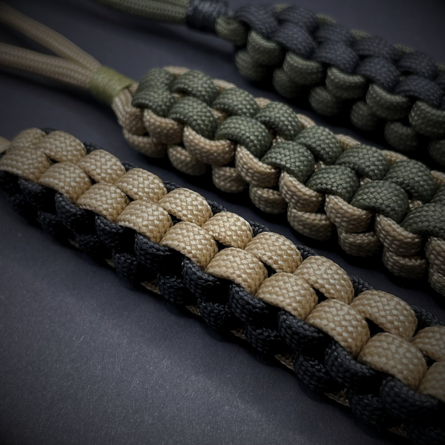 Flat lay of a 3 550 Paracord knife lanyards on a dark grey background