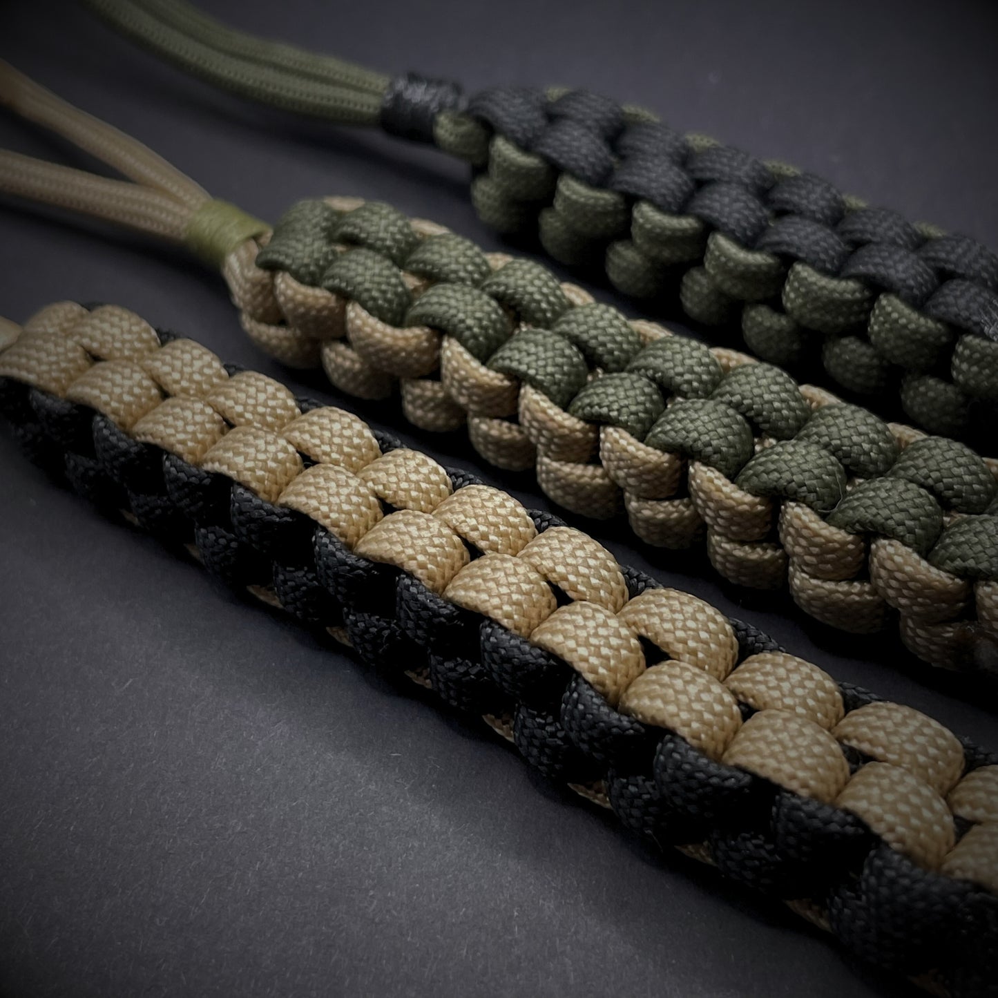 Flat lay of a 3 550 Paracord knife lanyards on a dark grey background