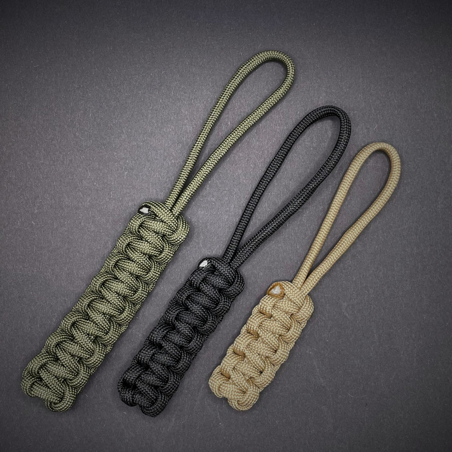 Flat lay of 3 550 Paracord knife lanyards on a dark grey background