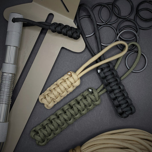 Flat lay of 3 550 Paracord knife lanyards on a dark grey background