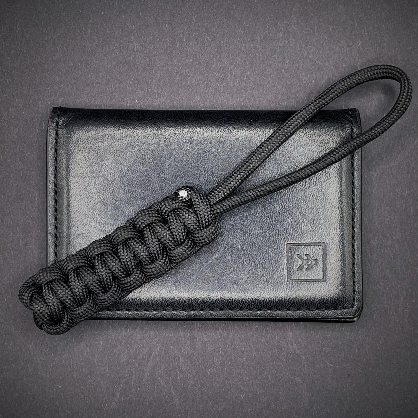 Flat lay of a back 550 Paracord knife lanyards on a dark grey background