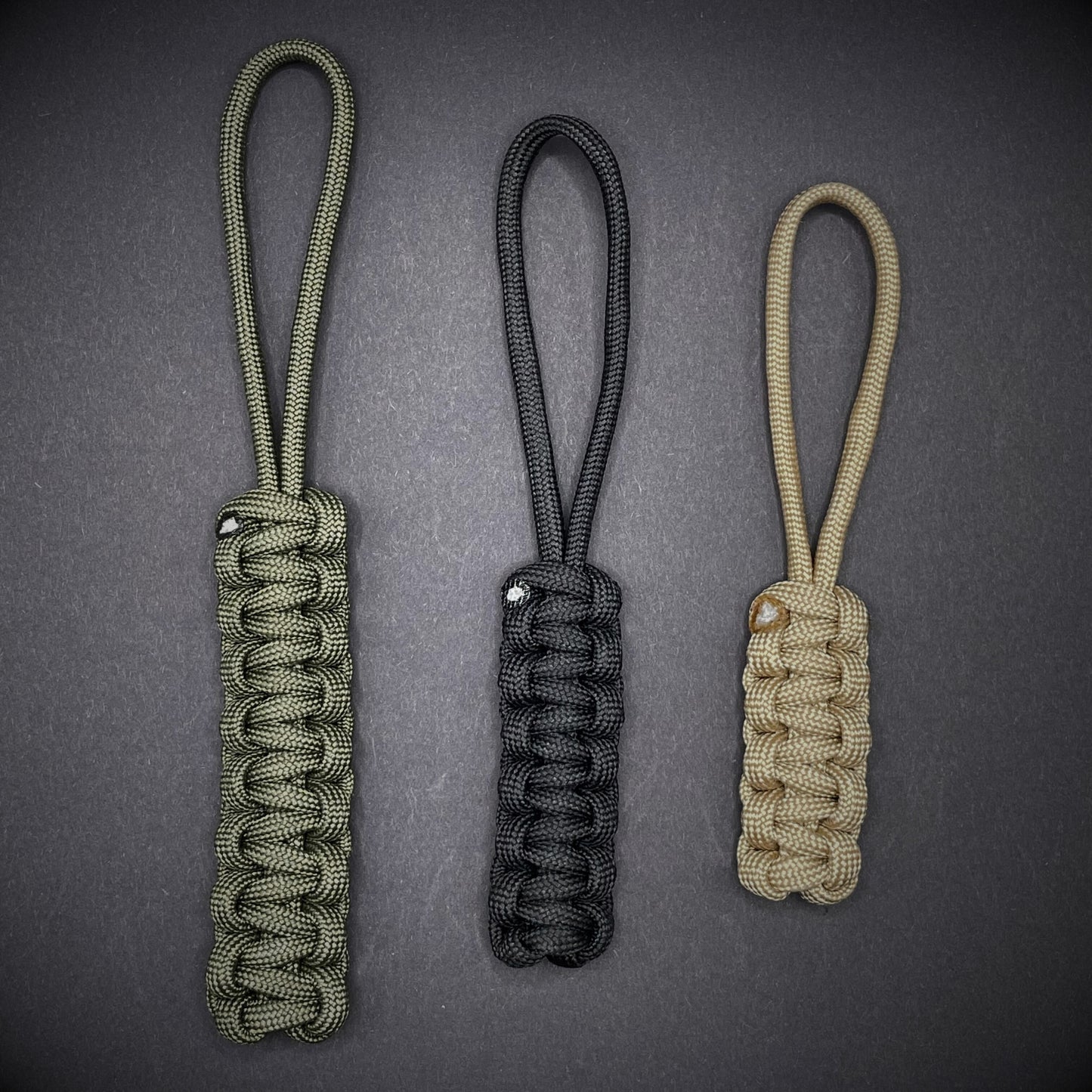 Flat lay of a 3 550 Paracord knife lanyards on a dark grey background