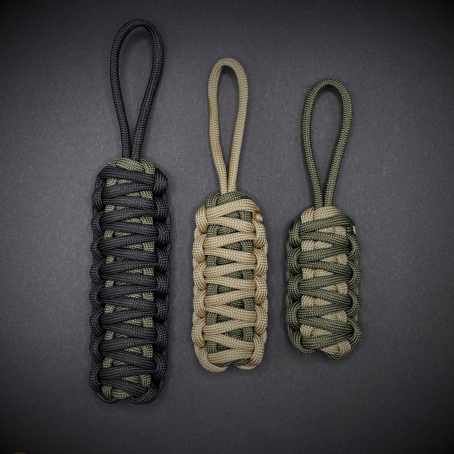 Flat lay of 3 550 Paracord knife lanyards on a dark grey background