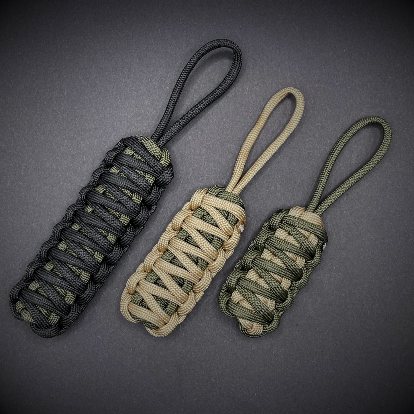 Flat lay of 3 550 Paracord knife lanyards on a dark grey background
