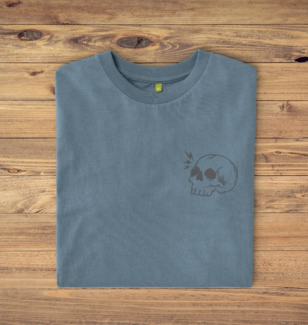 Folded Stone blue t-shirt on a oak panelled background, the t-shirt has a skull logo print.