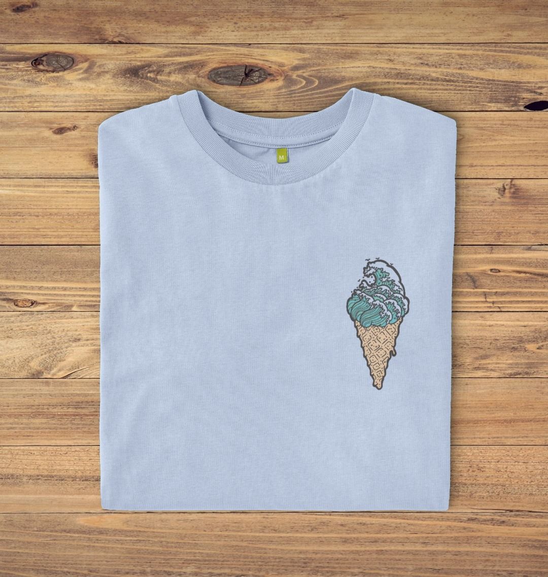Folded Stone blue t-shirt on a oak panelled background, the t-shirt has an ice cream waves logo print.