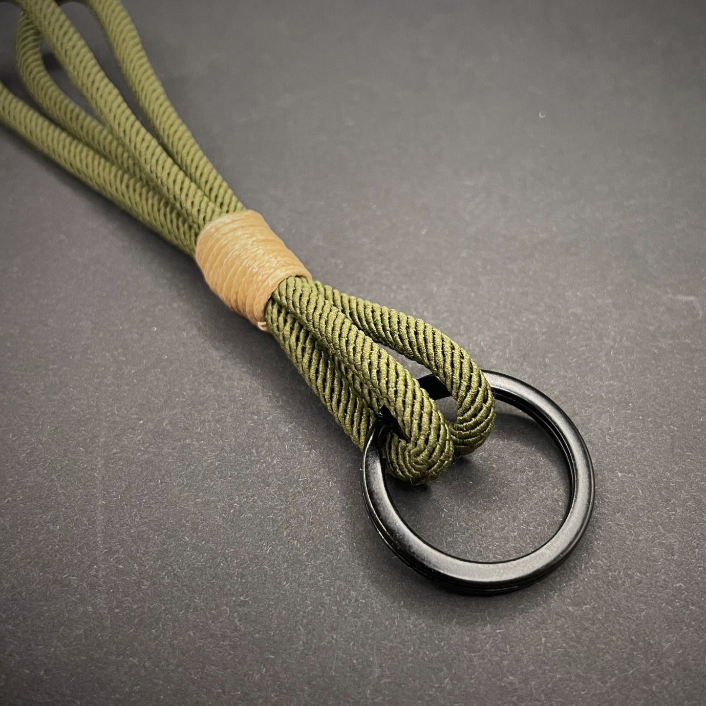Flat lay of Green Milan Rope keychain with tan cotton whipping on a dark background.
