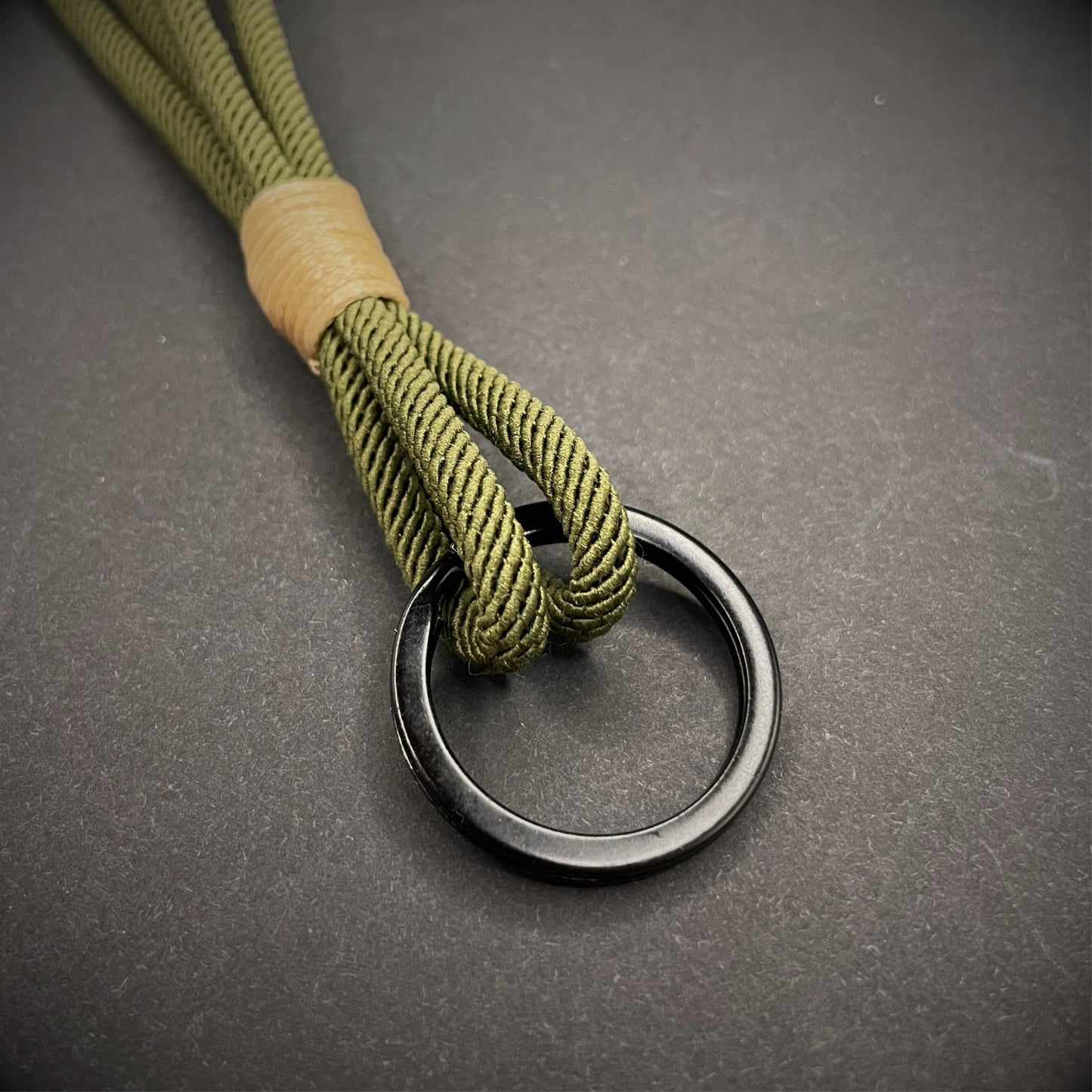 Flat lay of Green Milan Rope keychain with tan cotton whipping on a dark background.
