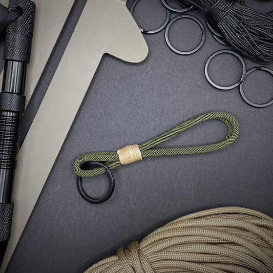 Flat lay of Green Milan Rope keychain with tan cotton whipping on a dark background.