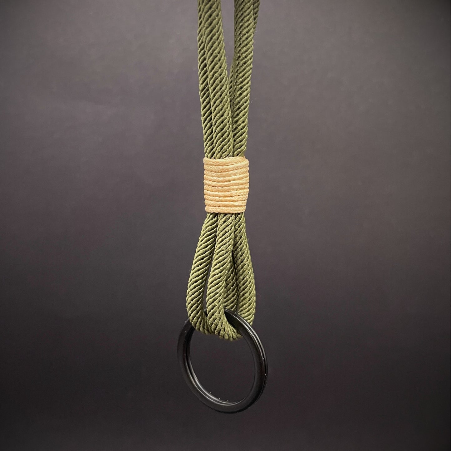 Flat lay of Green Milan Rope keychain with tan cotton whipping on a dark background.