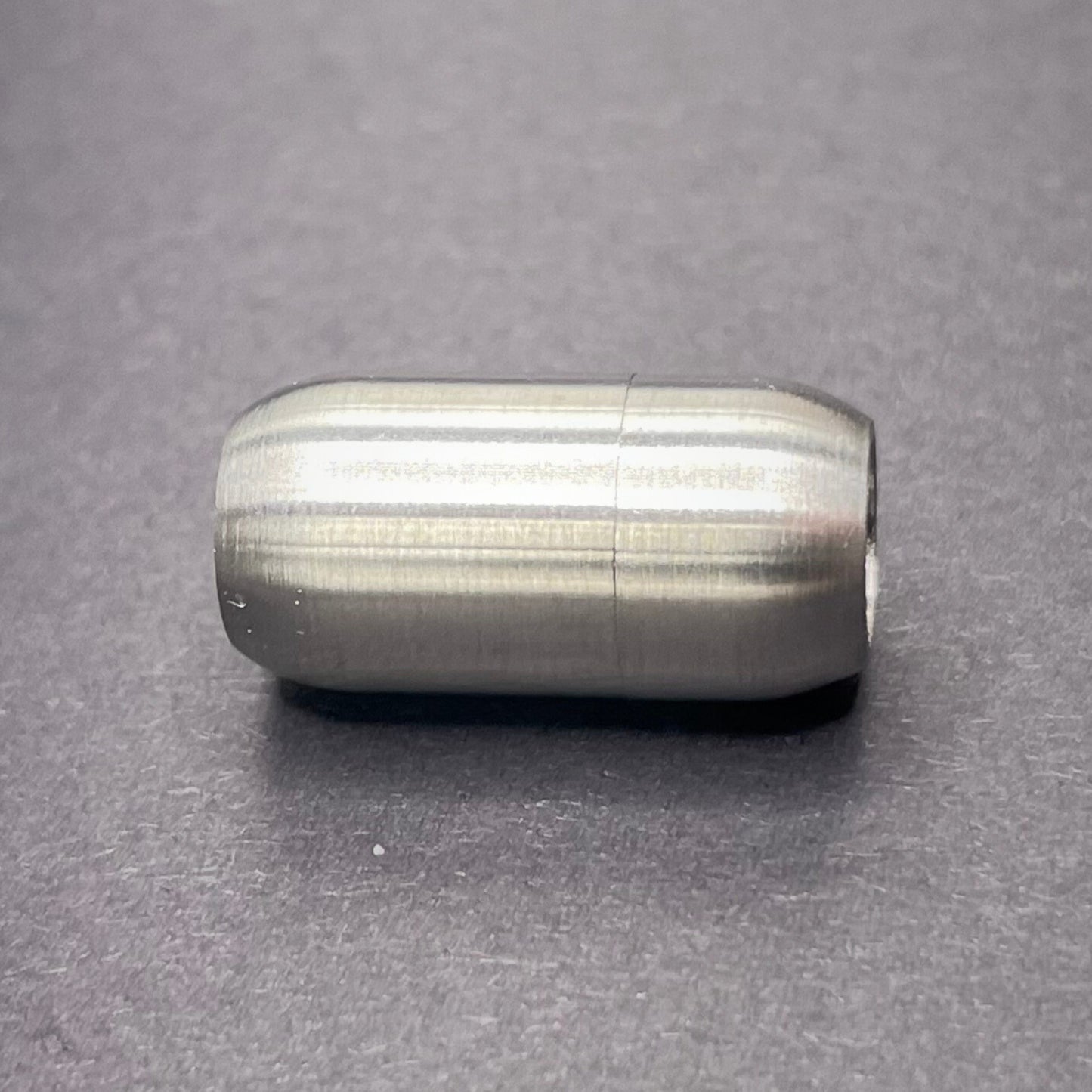 Stainless Steel cylindrical metal magnetic bracelet clasp, displayed on a dark textured background.
