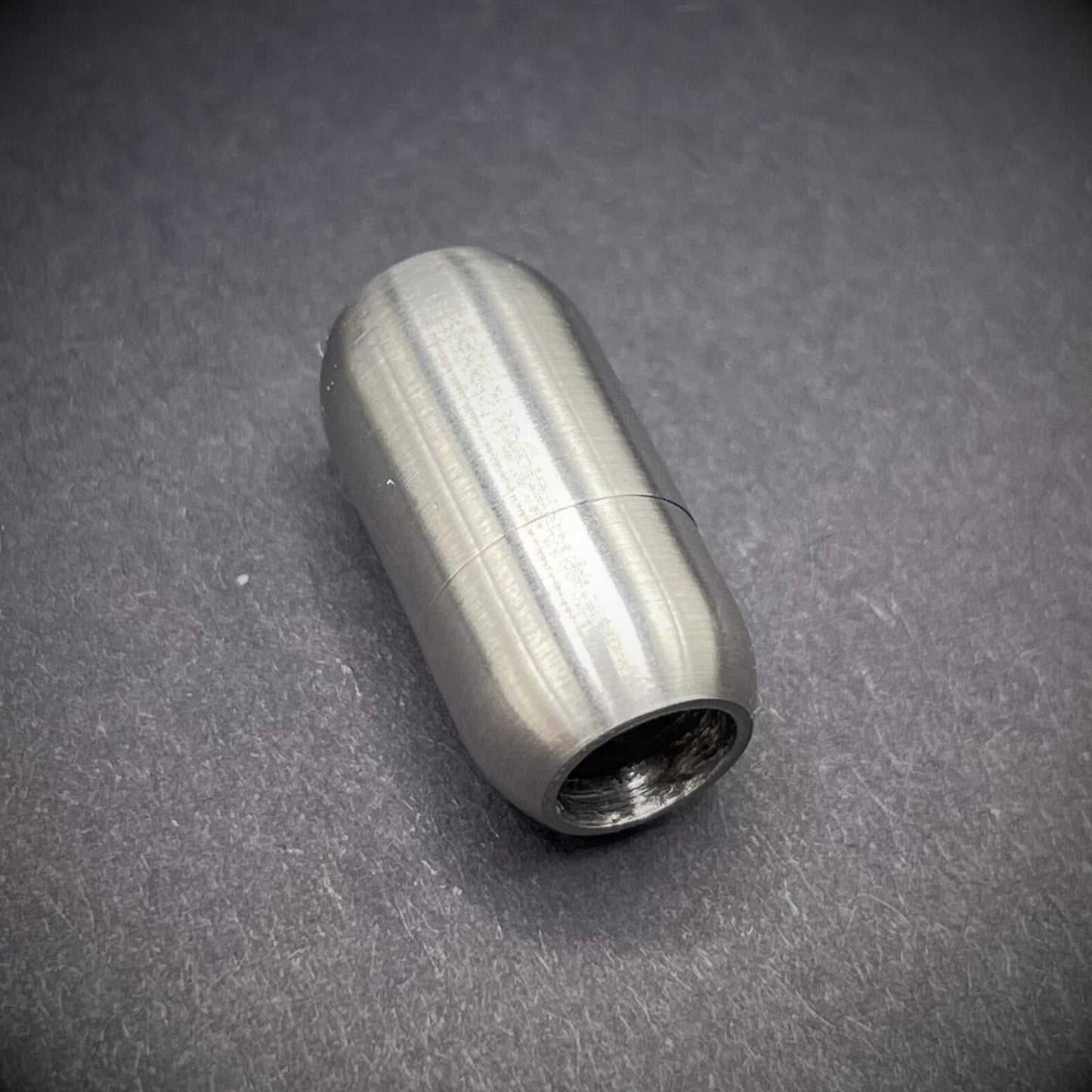 Stainless Steel cylindrical metal magnetic bracelet clasp, displayed on a dark textured background.