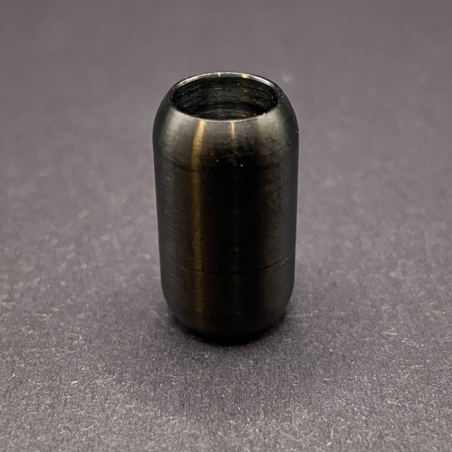 Black cylindrical metal magnetic bracelet clasp, displayed on a dark textured background.
