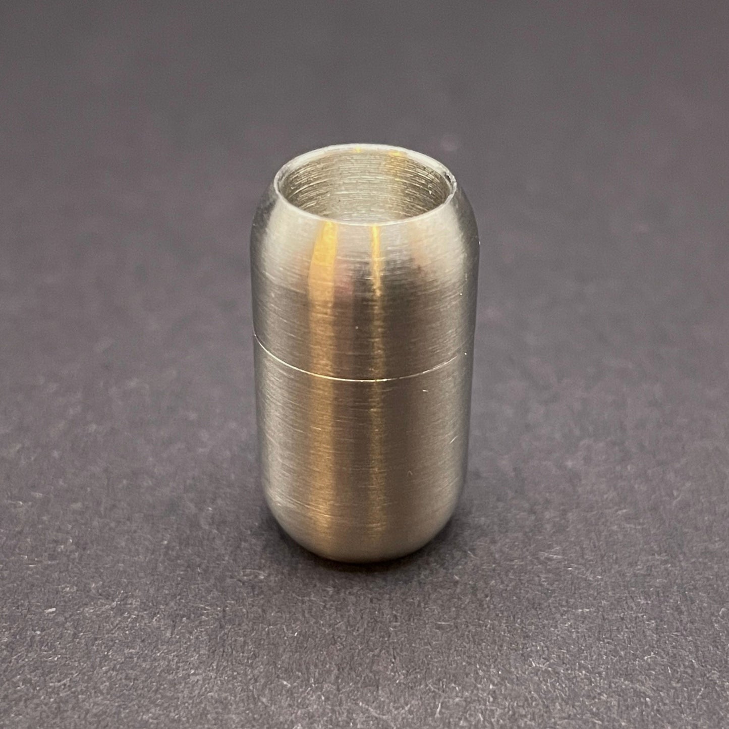 Stainless Steel cylindrical metal magnetic bracelet clasp, displayed on a dark textured background.