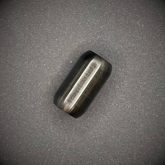 Black cylindrical metal magnetic bracelet clasp, displayed on a dark textured background.