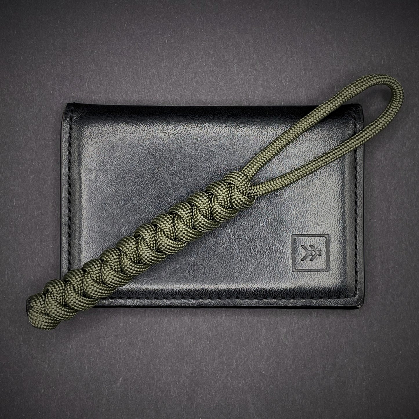 Flat lay of a 3 550 Paracord knife lanyards on a dark grey background