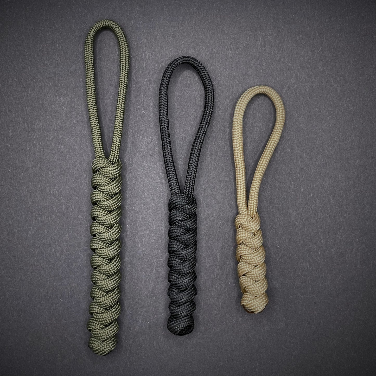 Flat lay of a 3 550 Paracord knife lanyards on a dark grey background