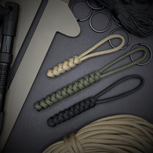 Flat lay of a 3 550 Paracord knife lanyards on a dark grey background