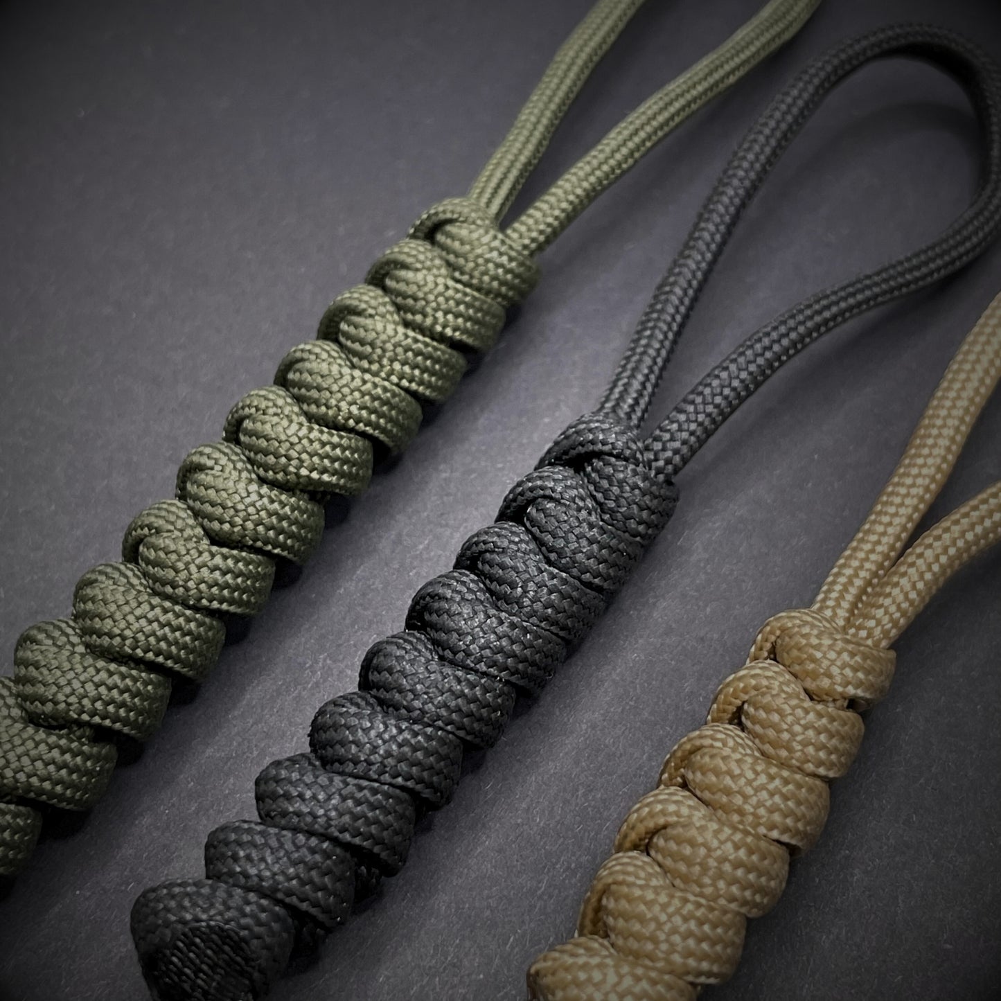 Flat lay of a 3 550 Paracord knife lanyards on a dark grey background