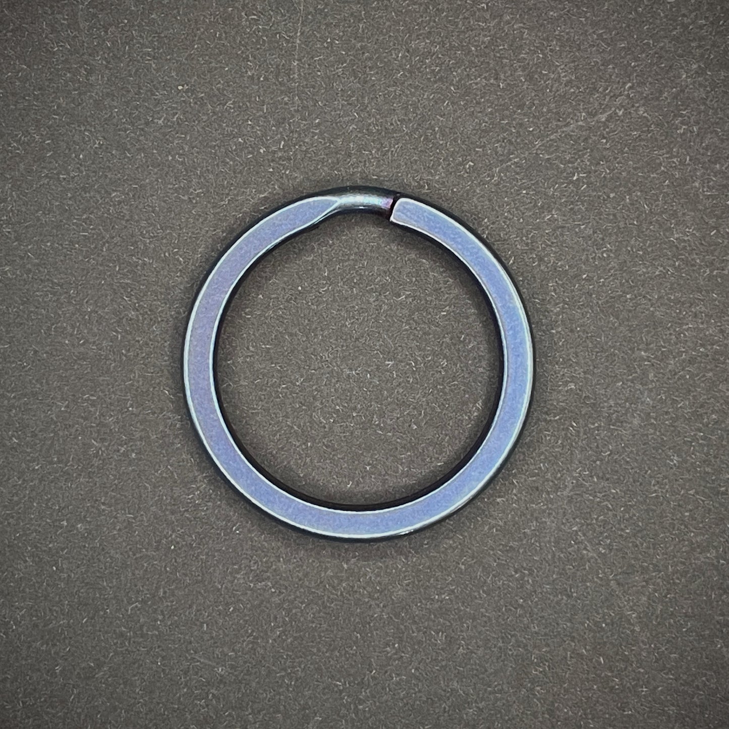 A Blue Titanium Split Ring on a dark grey background