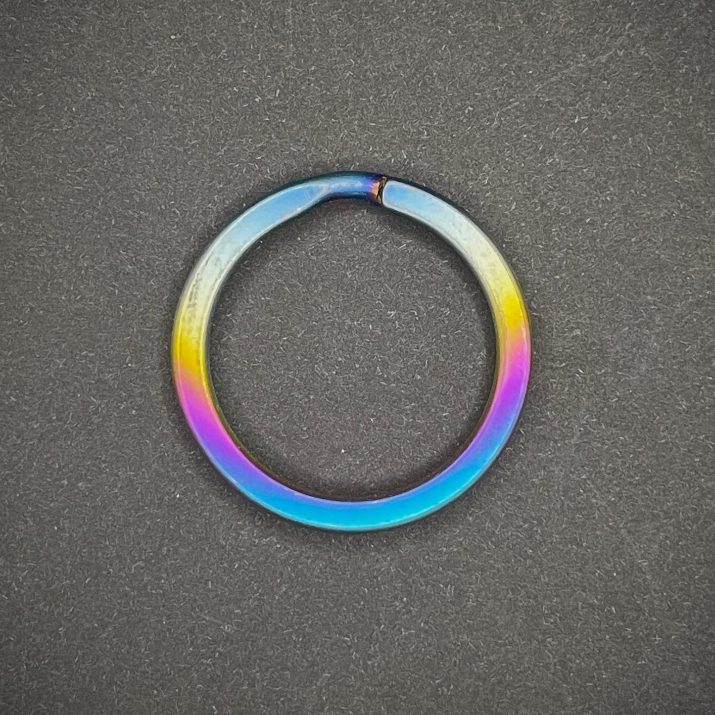 A Sunset Titanium Split Ring on a dark grey background