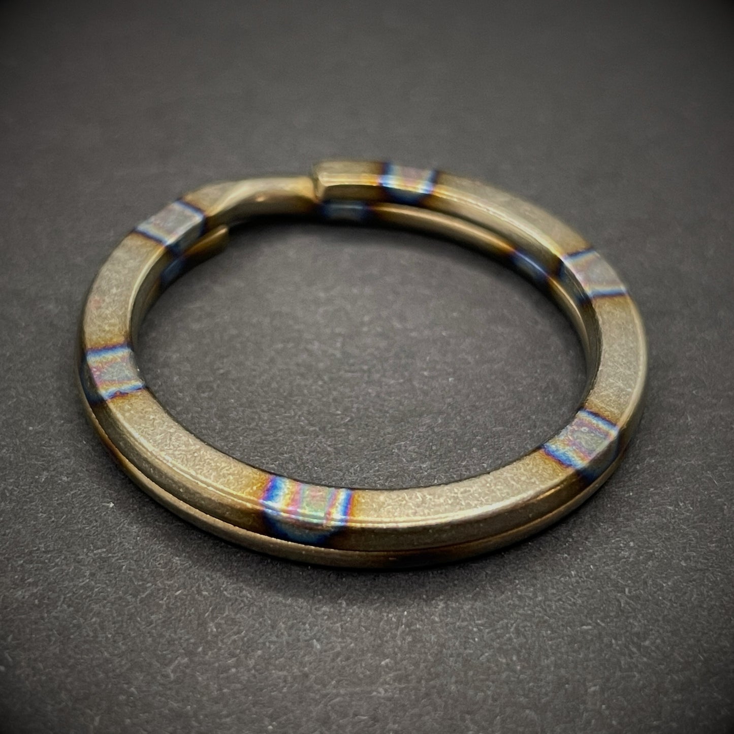 A Zebra Titanium Split Ring on a dark grey background