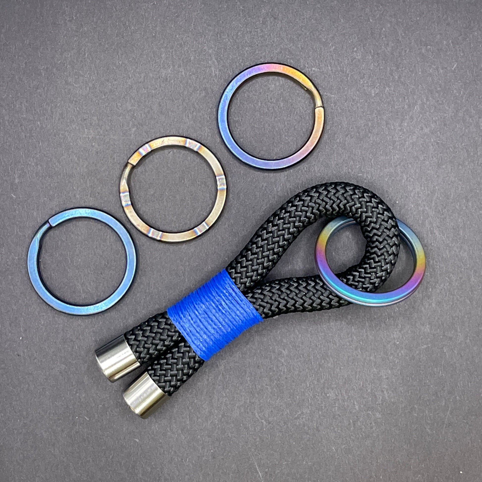 Keychain with colourful titanium split rings and blue strap on a grey background