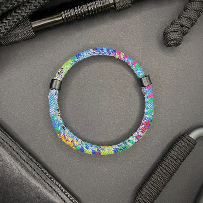 Light Blue Boho rope bracelet with black sliding clasps, displayed on a dark grey surface with EDC gear in the background.