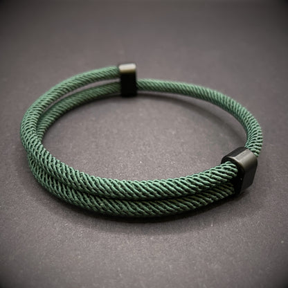 Forrest Green Milan rope bracelet with black sliding clasps, displayed on a dark grey surface.