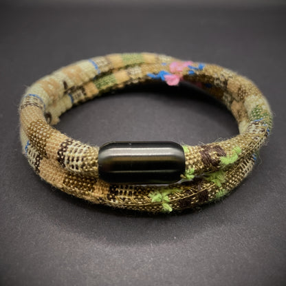 Khaki Boho rope bracelet with black magnetic clasps, displayed on a dark grey surface.