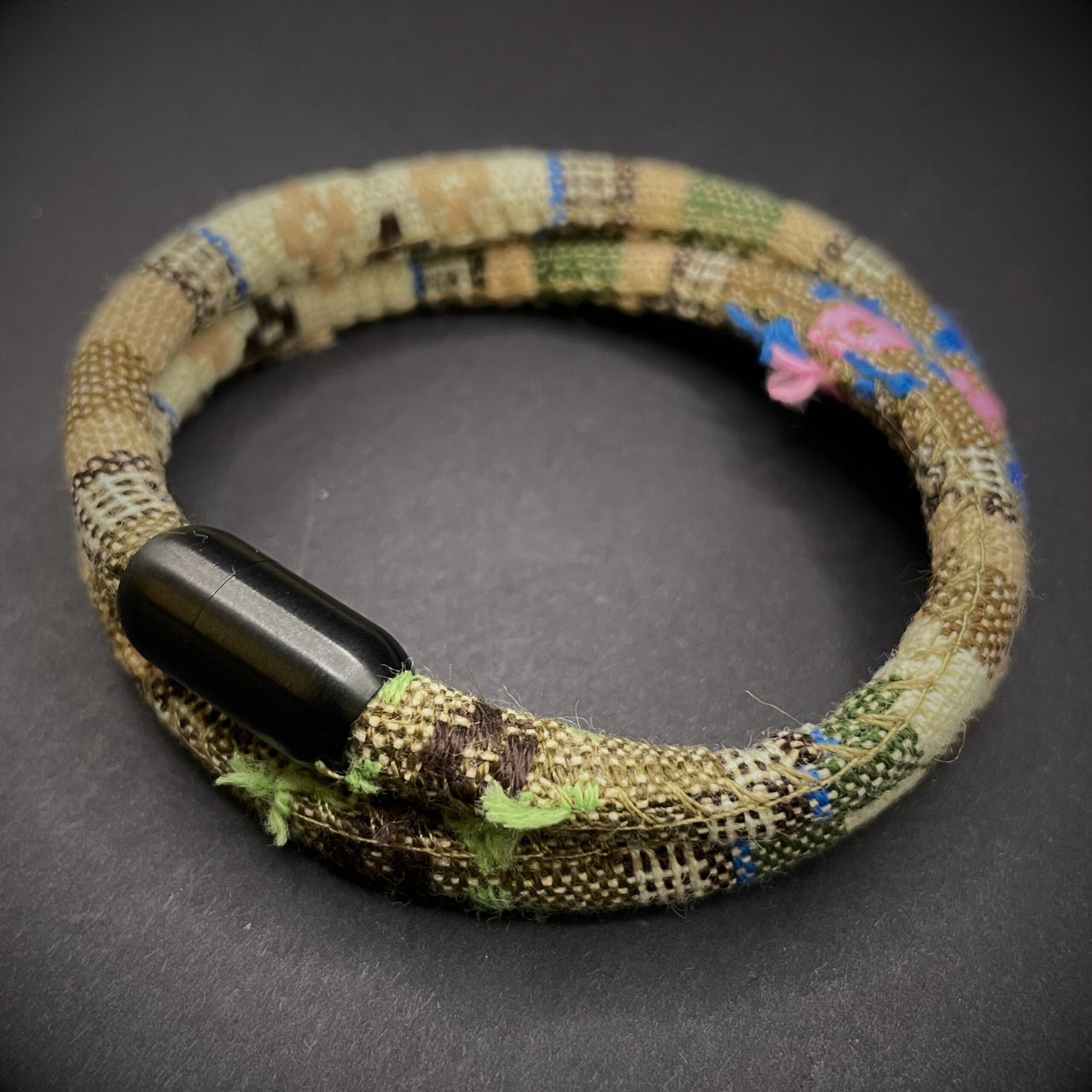Khaki Boho rope bracelet with black magnetic clasps, displayed on a dark grey surface.