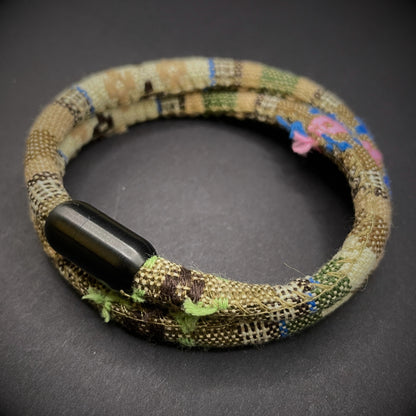 Khaki Boho rope bracelet with black magnetic clasps, displayed on a dark grey surface.
