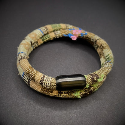 Khaki Boho rope bracelet with black magnetic clasps, displayed on a dark grey surface.