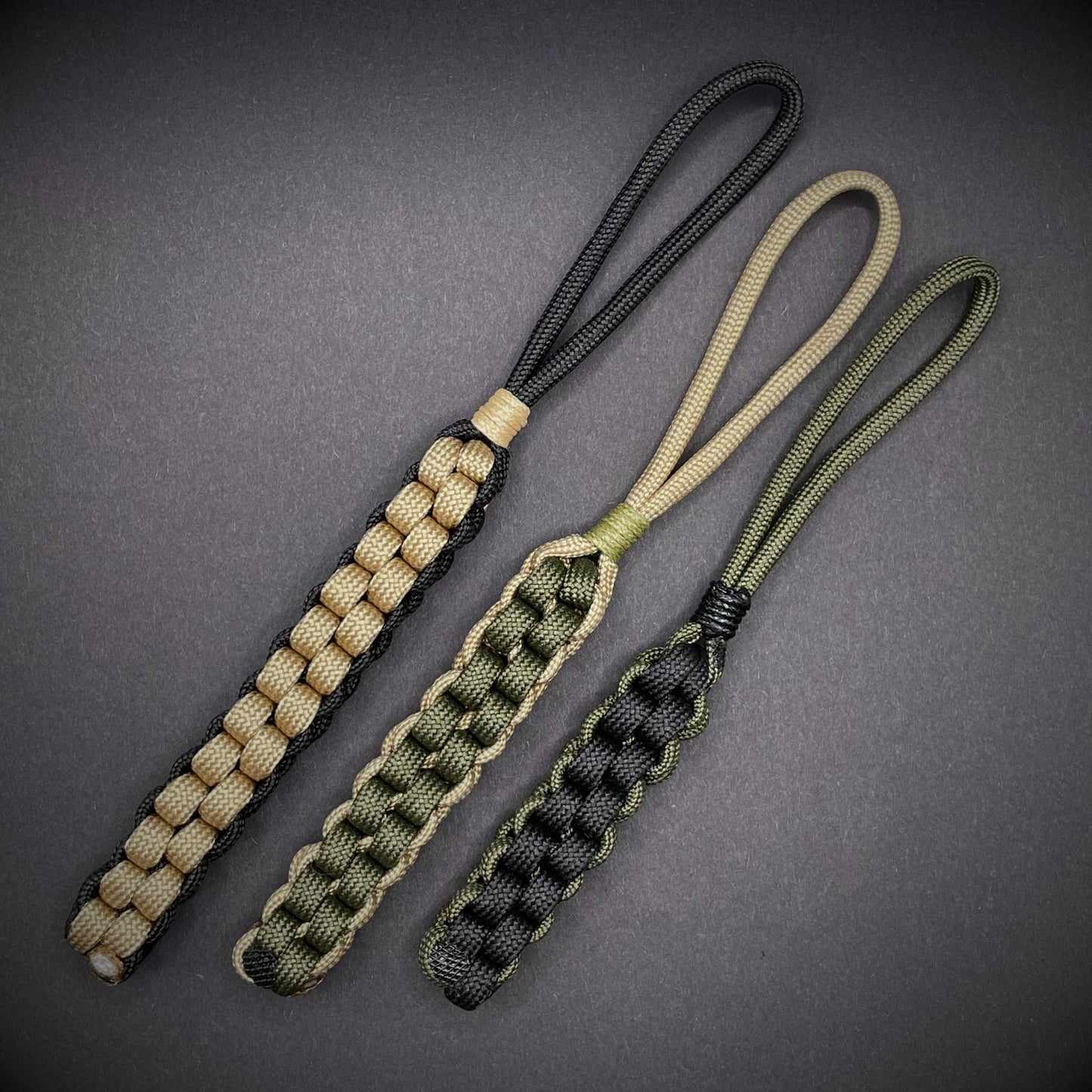 Flat lay of 3 550 Paracord knife lanyards on a dark grey background