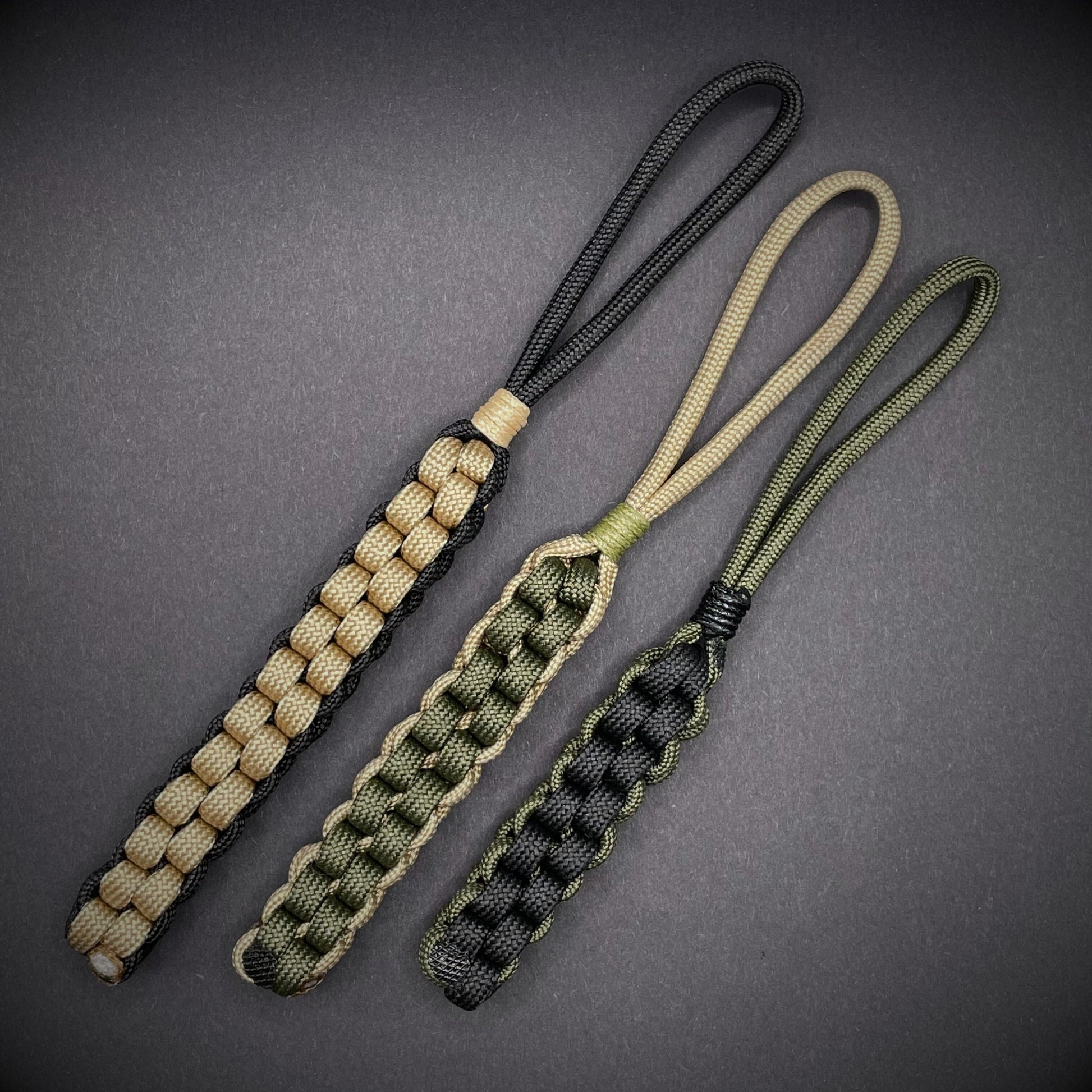 Flat lay of 3 550 Paracord knife lanyards on a dark grey background