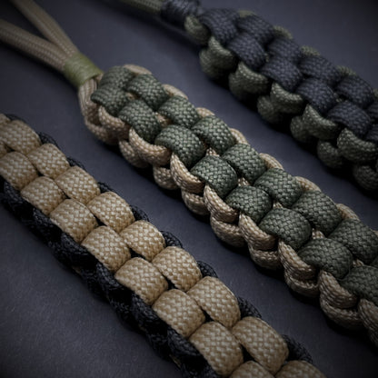 Flat lay of a 3 550 Paracord knife lanyards on a dark grey background