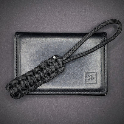 Flat lay of a back 550 Paracord knife lanyards on a dark grey background