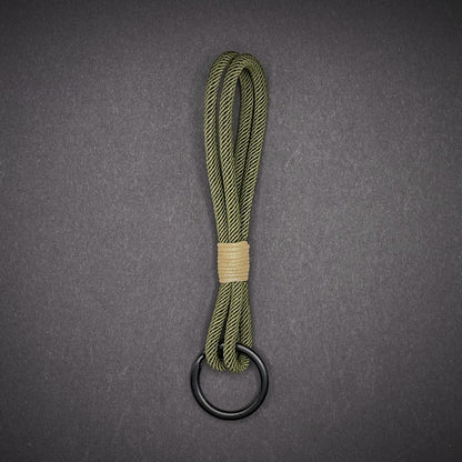 Flat lay of Green Milan Rope keychain with tan cotton whipping on a dark background.