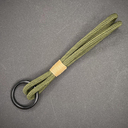 Flat lay of Green Milan Rope keychain with tan cotton whipping on a dark background.