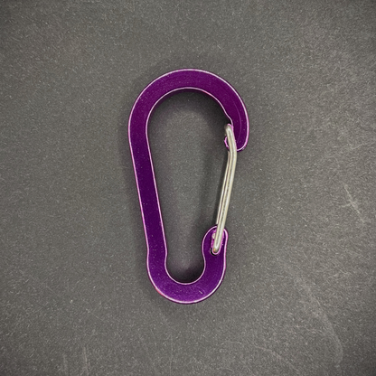 Purple Anodised aluminium carabiner, arranged on a dark surface.