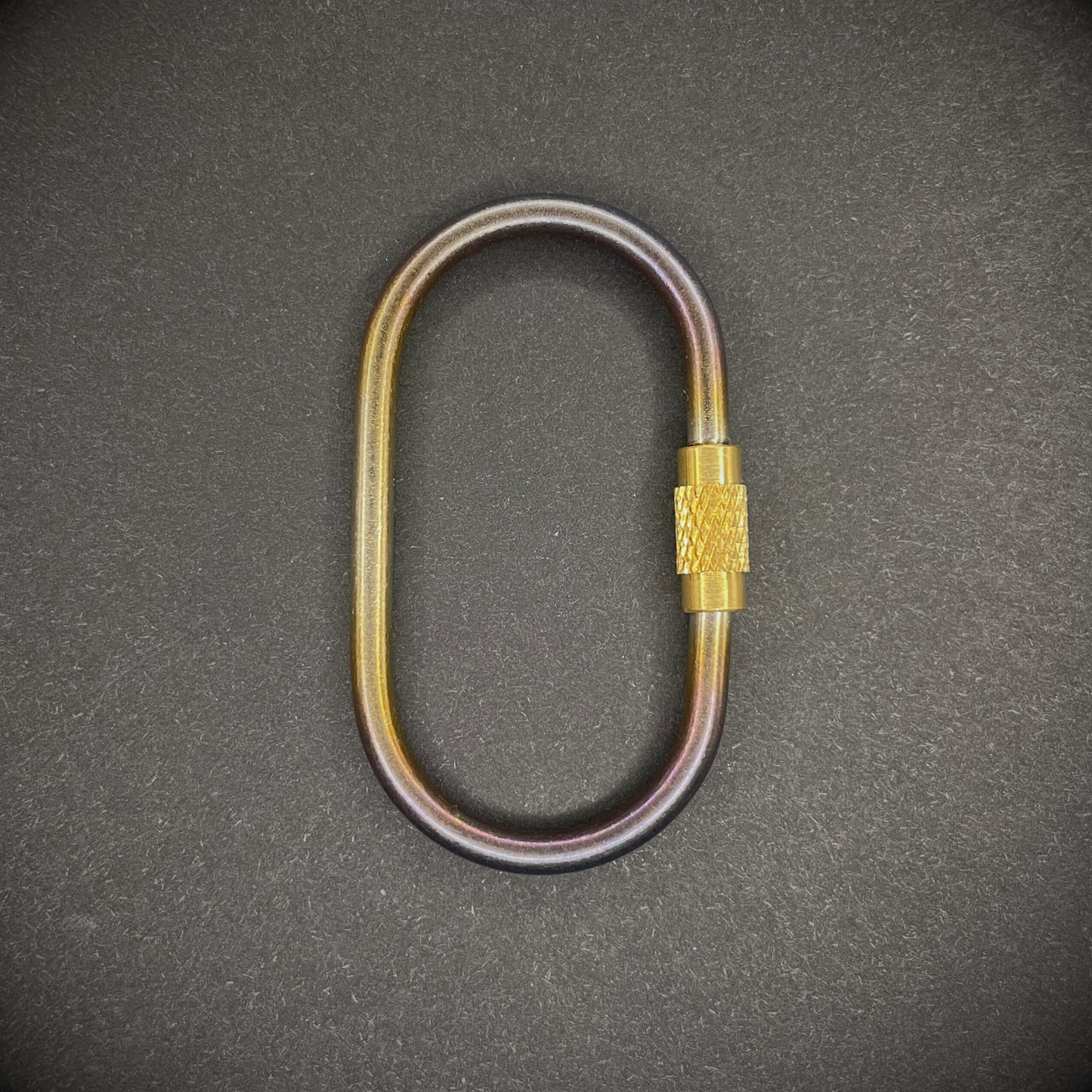 Mini Locking Titanium Carabiner arranged on a dark surface.