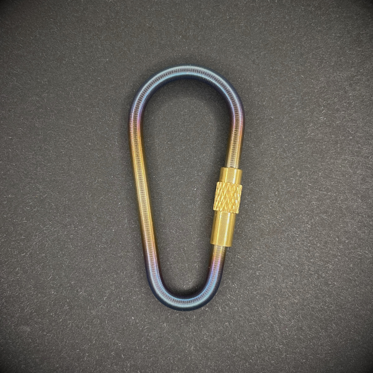 Mini Locking Titanium Carabiner arranged on a dark surface.