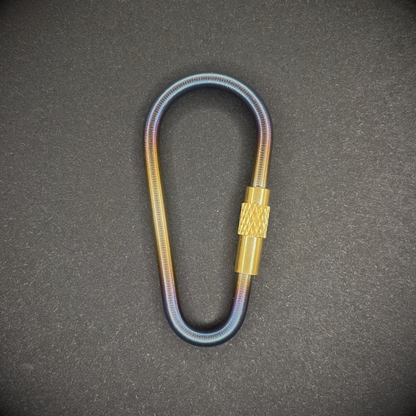 Mini Locking Titanium Carabiner arranged on a dark surface.