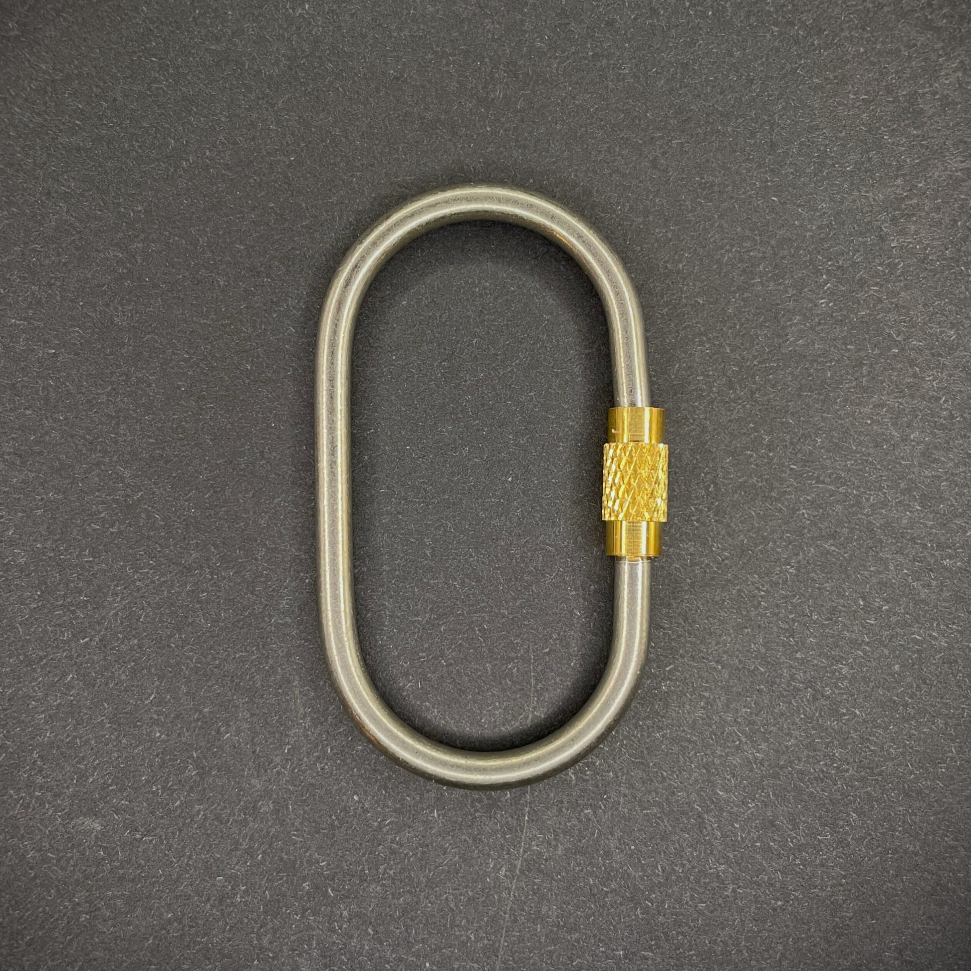 Mini Locking Titanium Carabiner arranged on a dark surface.
