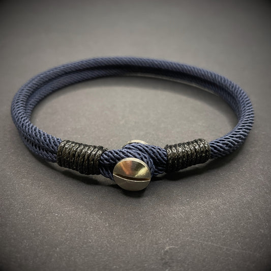 Close-up of a navy rope bracelet with a screw clasp and black whipping detail, displayed on a dark surface.