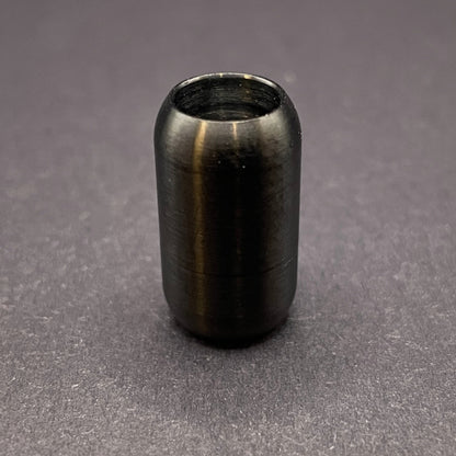 Black cylindrical metal magnetic bracelet clasp, displayed on a dark textured background.